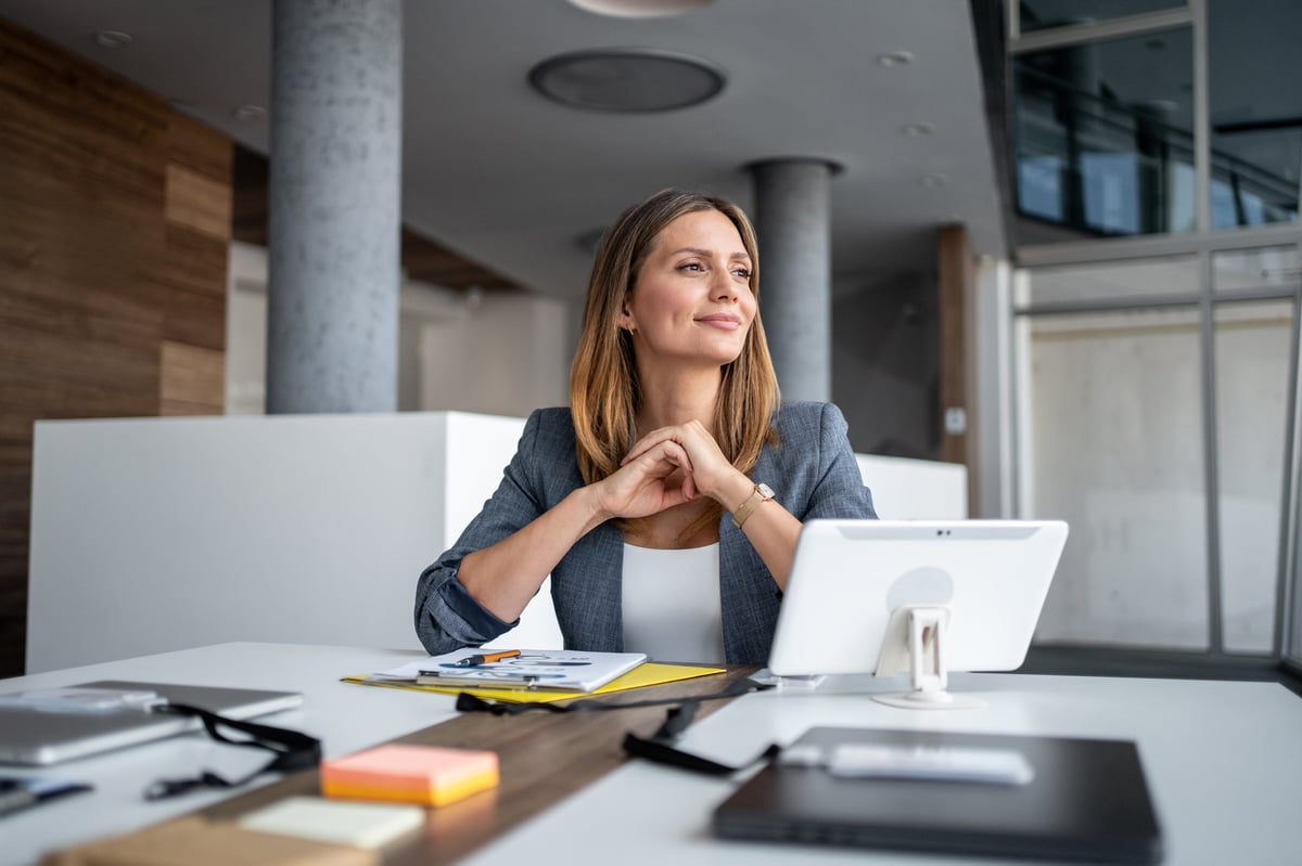 Businesswoman smiling at modern office desk, planning future business success