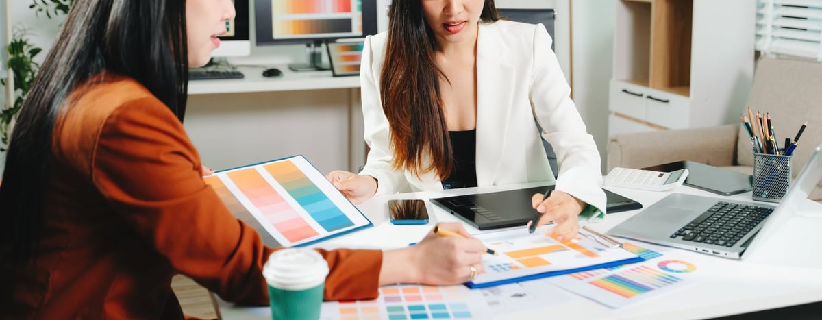 Two female designers collaborating on color palette and UX UI project in a modern creative office